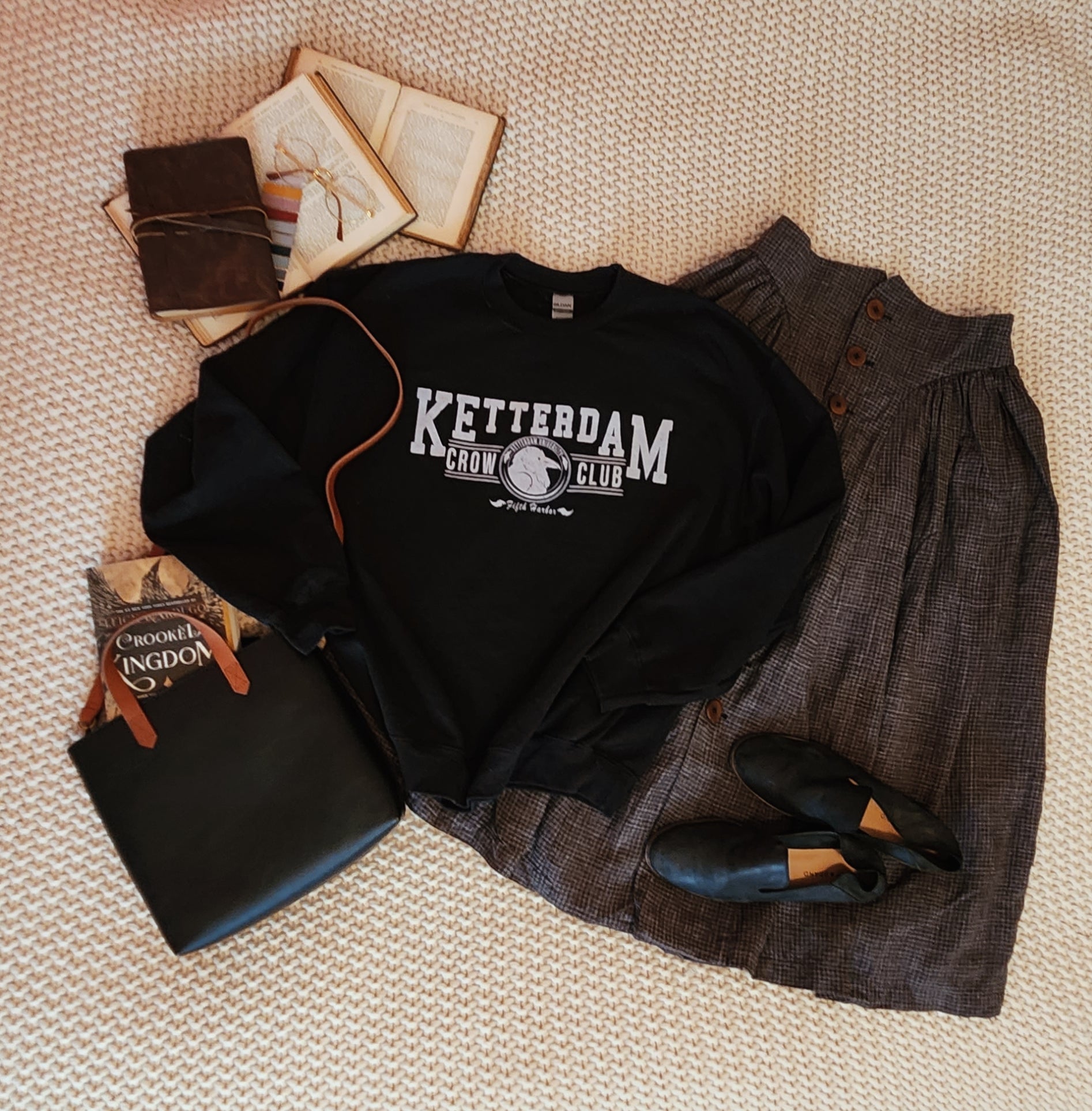 Ketterdam crow club university with crow logo sweatshirt styled in a dark academia style flatlay 