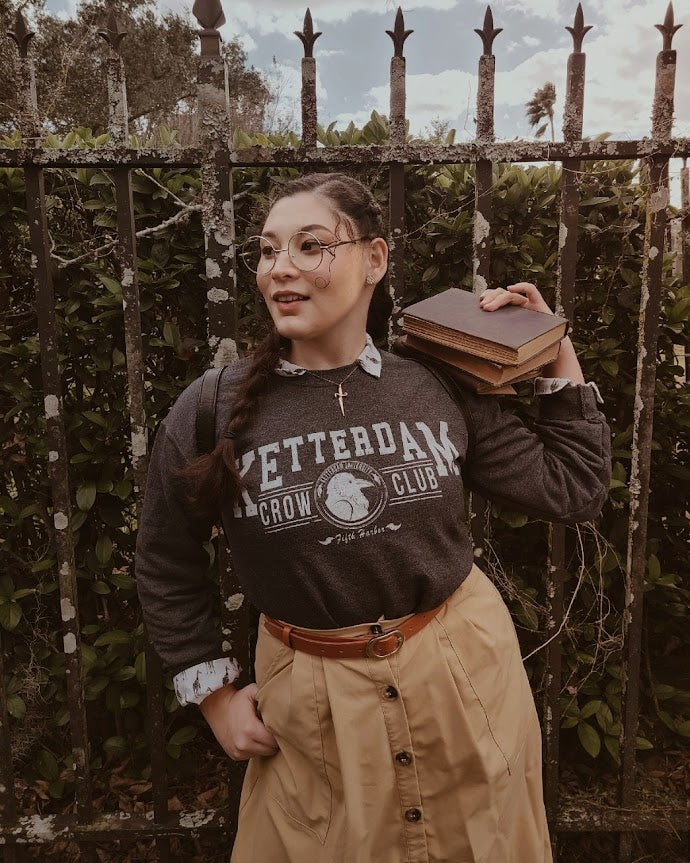 Ketterdam crow club university with crow logo sweatshirt worn by model by a woman in a dark academia style 