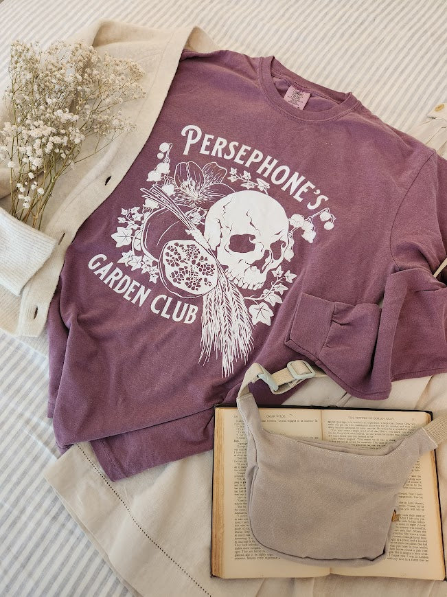 Persephone's Garden Club  long sleeve shirt in purple with pomegranates and skull styled in a flatlay with a white sweater