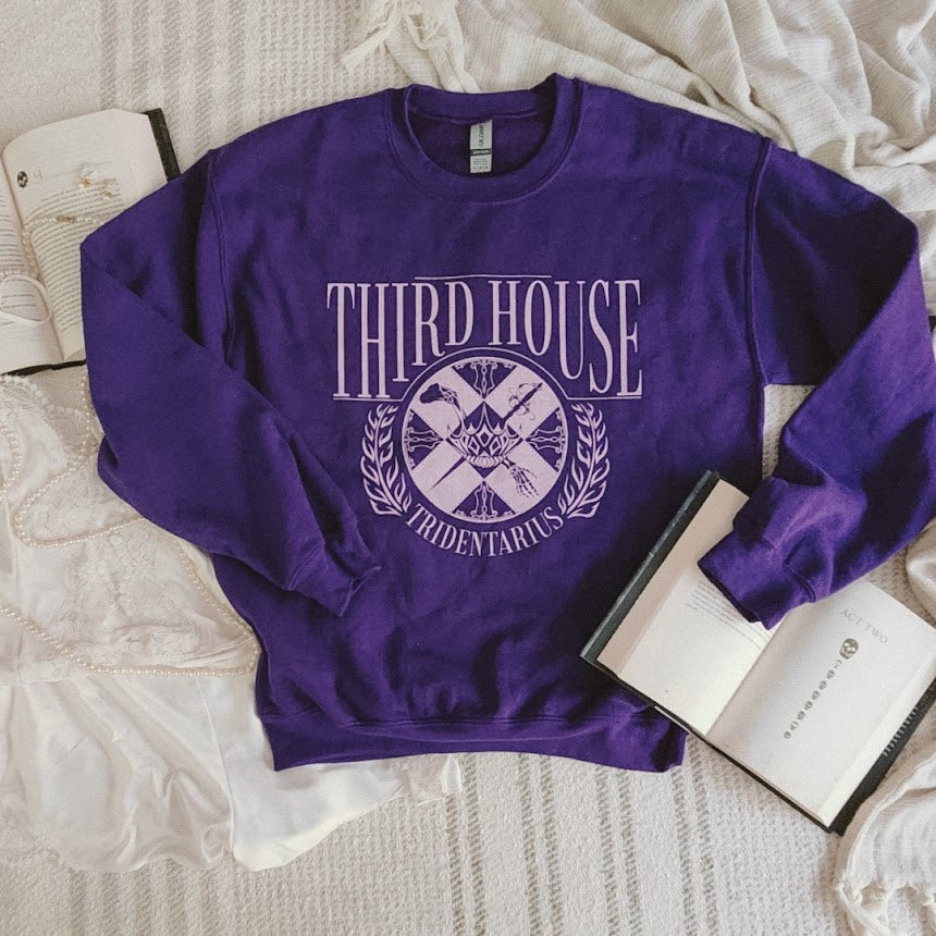 The locked tomb gideon the ninth third house sweatshirt in purple in a flatlay styled with harrow the ninth book